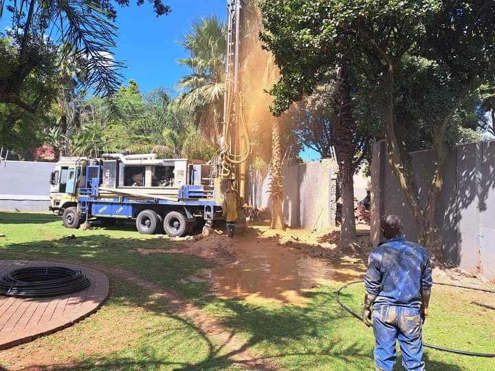 Water borehole drilling rig operating in a residential garden